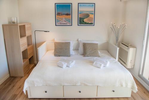- une chambre blanche avec un grand lit blanc et 2 oreillers dans l'établissement Pause Moulleau - terrasse et parking coeur Moulleau, à Arcachon