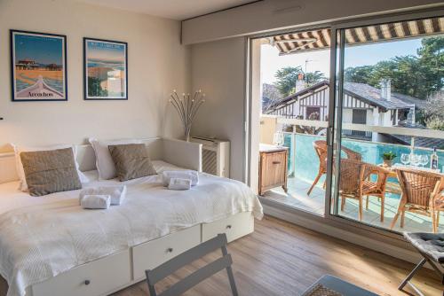 une chambre avec un grand lit et un balcon dans l'établissement Pause Moulleau - terrasse et parking coeur Moulleau, à Arcachon