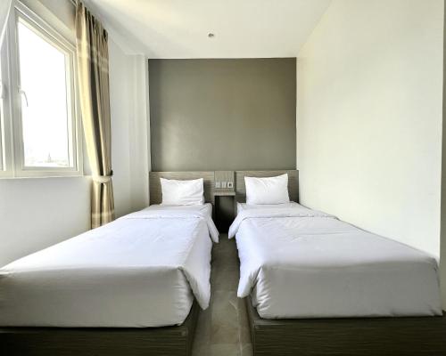 two twin beds in a room with a window at PURNAMA BALIGE HOTEL in Balige