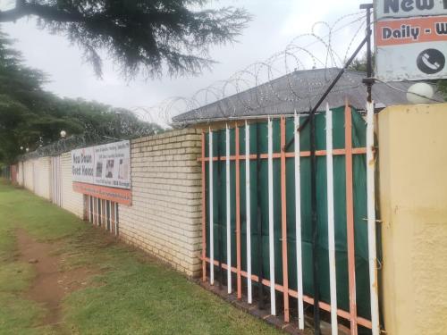 a building with a fence next to a street at New Dawn Guest House in Brakpan