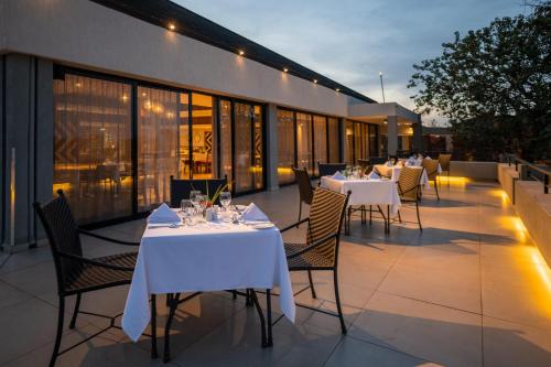 a restaurant with white tables and chairs on a patio at Mantis Akagera Game Lodge in Akagera