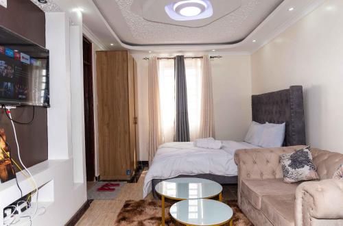 ein Wohnzimmer mit einem Sofa und einem Bett in der Unterkunft SpringStone Studio Apartment Rm 19 in Langata Rongai