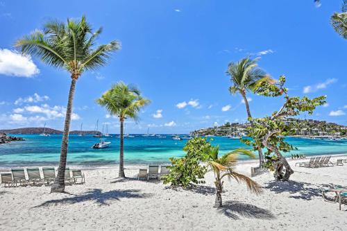 a beach with palm trees and a boat in the water at Elysian Resort Condo with 3 Balconies and Amenities! in St Thomas