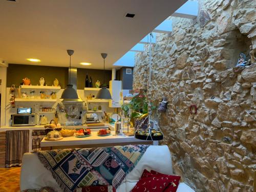 een woonkamer met een stenen muur en een bank bij Cal Bonic in Riudarenes