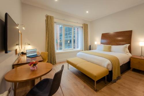 ein Hotelzimmer mit einem Bett, einem Schreibtisch und einem Tisch in der Unterkunft PREMIER SUITES Dublin, Leeson Street in Dublin