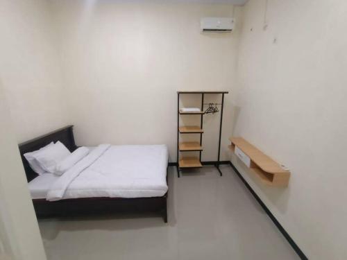 a white room with a bed and a shelf at Anugrah homestay in Cirebon