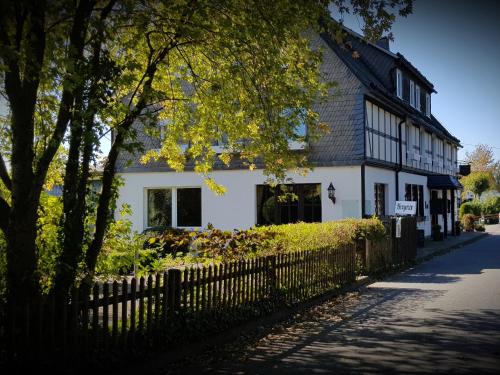 een wit huis met een hek ervoor bij Landschaftsgasthaus Schanze 1 in Schmallenberg