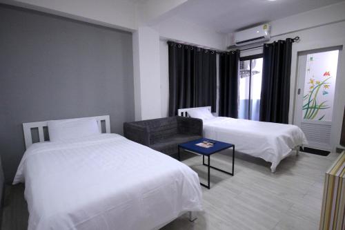 a hotel room with two beds and a couch at Sakun Place in Bangna