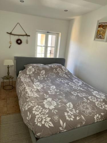 een slaapkamer met een bed met een deken erop bij Maison Chezanne in Magalas