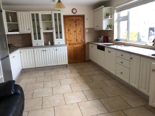 a kitchen with white cabinets and a tile floor at Eden House in Carlingford