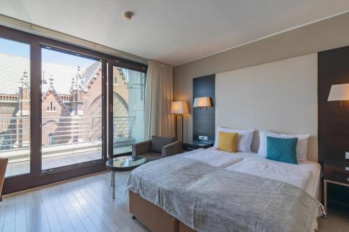 a bedroom with a large bed and a large window at Lion's Garden Hotel in Budapest