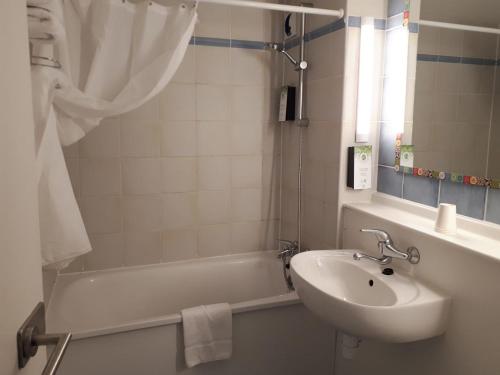 een badkamer met een wastafel en een bad met een wastafel bij Kyriad Blois Nord in Blois