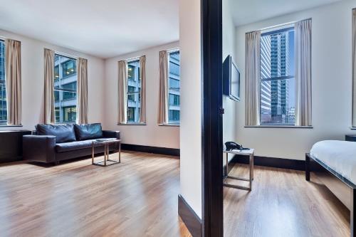 a room with a bed and a couch and windows at Eurostars Wall Street in New York