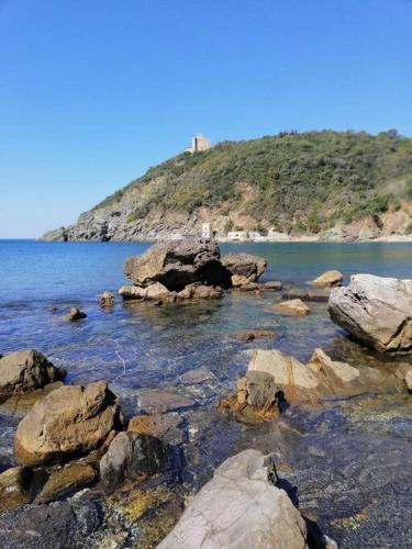 a body of water with rocks and a hill at Rosemary’s Home in Quercianella