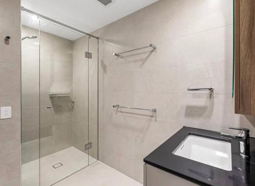 a bathroom with a glass shower with a sink at Stylish Stay for Couples in CBD by Stylish Stays in Brisbane