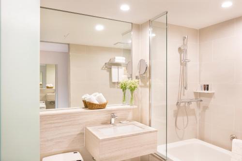 a white bathroom with a sink and a shower at Eldis Regent Hotel in Daegu