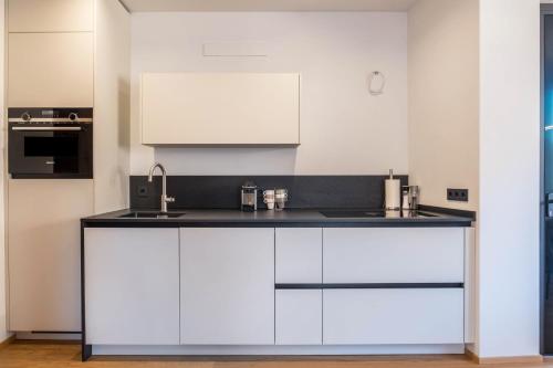 a kitchen with white cabinets and a sink at Falsers Mountain Lodge in Cornedo all'Isarco