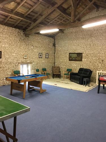 a room with a ping pong table and chairs at Logis de L'Arceau in Celles