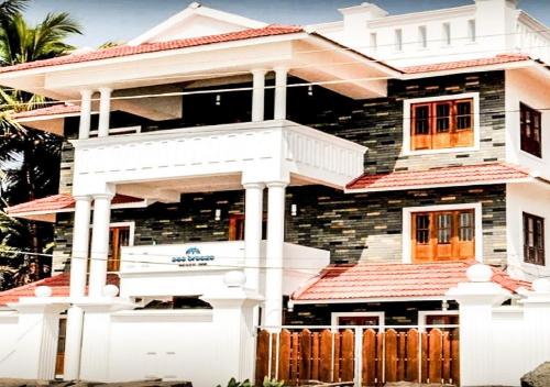 a house with a white fence in front of it at Sea Breeze Beach Inn in Kannur