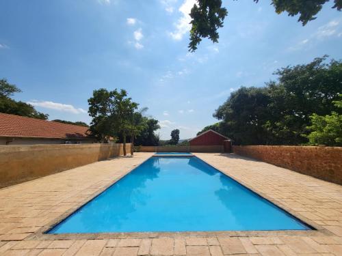 a large blue swimming pool with a brick wall at Guesthouse Serenity in Hartbeespoort
