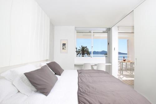 a white bedroom with a bed and a view of the ocean at Apartment Sivella in Pollença