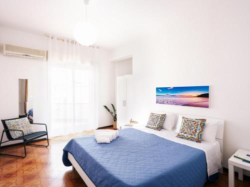 ein weißes Schlafzimmer mit einem blauen Bett und einem Stuhl in der Unterkunft Limoncello Home con Veranda vista Mare a 3 Min dalla spiaggia in Alcamo