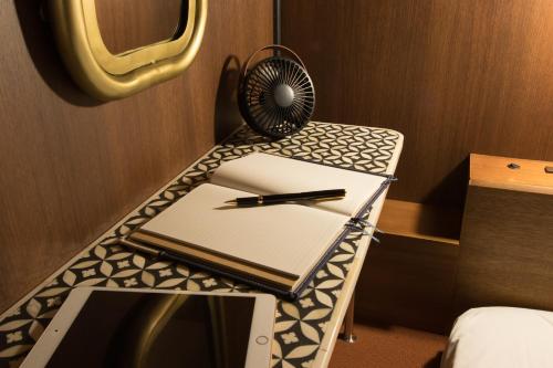 a desk with a notebook and a pen on it at HARE-TABI SAUNA & INN Yokohama - ハレタビ - in Yokohama