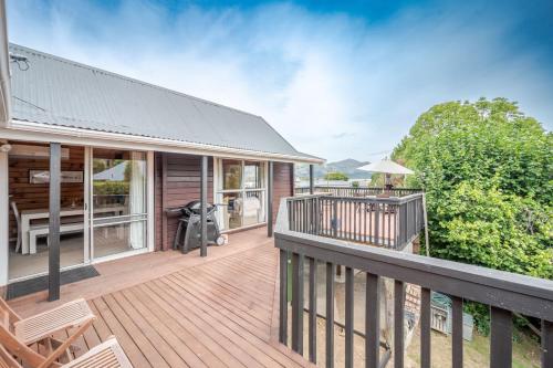 a house with a deck with a table and chairs at Maison en Noyer - Akaroa Holiday Home in Akaroa
