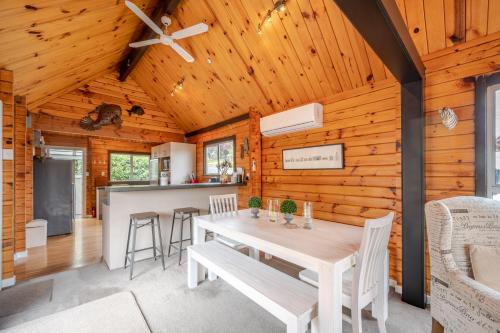 a dining room with a table and a kitchen at Maison en Noyer - Akaroa Holiday Home in Akaroa