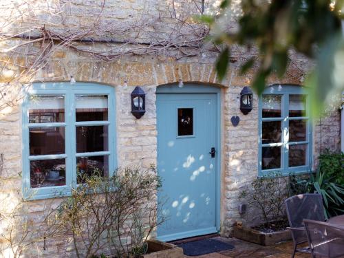 uma casa com uma porta azul e duas janelas em Thimble Cottage em Lower Slaughter