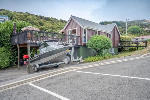 a house with a boat parked in front of it at Maison en Noyer - Akaroa Holiday Home in Akaroa