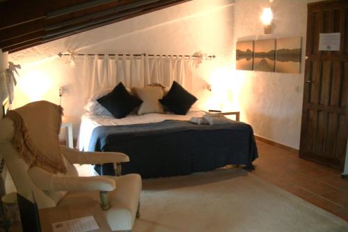 um quarto com uma cama e uma cadeira num quarto em Casa KiSi Cottage, Rural Boutique Bed & Breakfast em Málaga