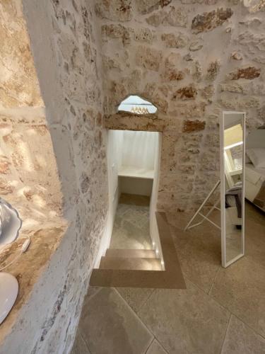 un bagno in pietra con lavandino e specchio di white room Ostuni a Ostuni