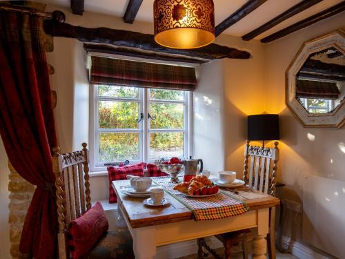jadalnia ze stołem i oknem w obiekcie Thimble Cottage w mieście Lower Slaughter