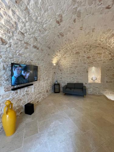 a living room with a tv on a stone wall at white room Ostuni in Ostuni