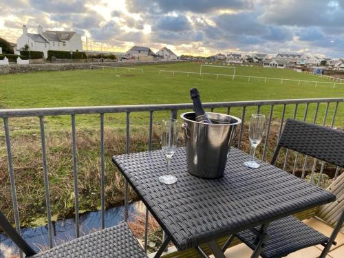 a table with a bottle of wine and glasses on a balcony at Beach Retreat-3 Bed-Pet friendly-Central location in Trearddur