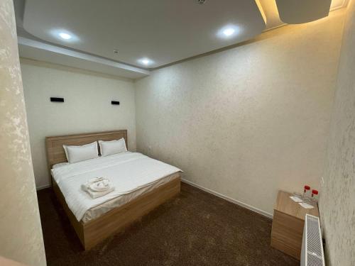 a small bedroom with a bed with white sheets at Chinor Hotel Fergana in Fergana