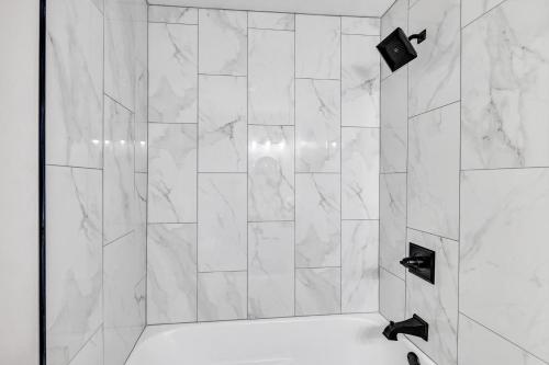 a bathroom with a shower with white marble tiles at Hazelwood Haven near Lambeau! Duplex in Green Bay