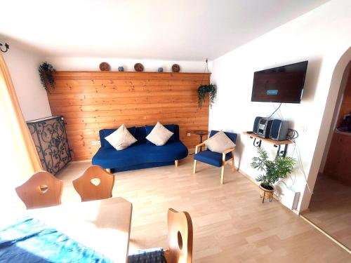 uma sala de estar com um sofá azul e uma televisão em Gästehaus u Ferienwohnungen Veronika incl Frühstücksbuffet und KönigsCard mit 200 kostenlosen Attraktionen em Unterammergau