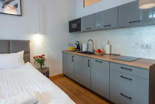 a kitchen with white cabinets and a bed in a room at PROVENIR HOME KWIATOWA 5 in Poznań
