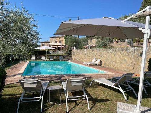 a pool with an umbrella and chairs and a table with an umbrella at Podere Zelmira in Sinalunga