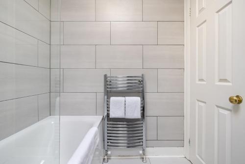 La salle de bains blanche est pourvue d'un porte-serviettes et d'une baignoire. dans l'établissement The London Crib - Relaxing 1BDR Flat with Terrace, à Londres