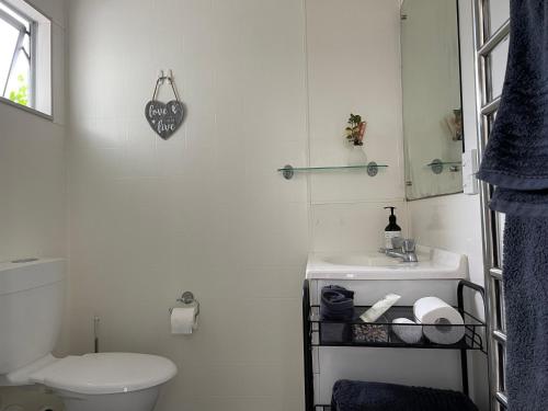 a white bathroom with a toilet and a sink at family friendly 3BR flat - 3min walk to the beach - self contained in Auckland