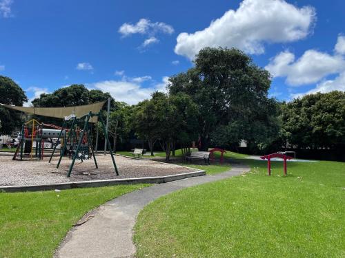a park with a swing set and a playground at family friendly 3BR flat - 3min walk to the beach - self contained in Auckland