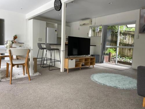 a living room with a tv and a table with chairs at family friendly 3BR flat - 3min walk to the beach - self contained in Auckland