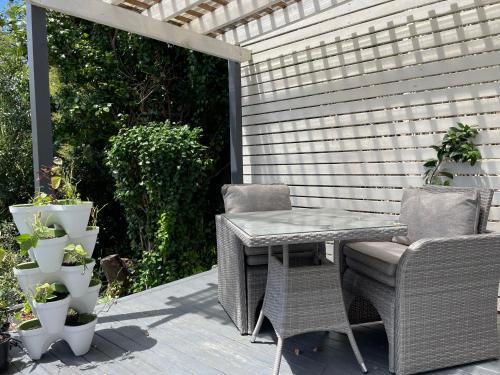 a patio with a table and a chair and some plants at family friendly 3BR flat - 3min walk to the beach - self contained in Auckland