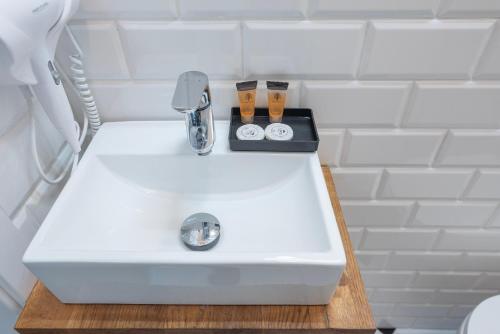 a white sink with two clocks on top of it at PROVENIR HOME KWIATOWA 5 in Poznań