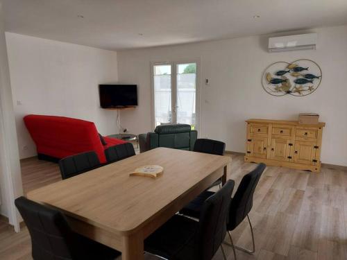 a living room with a wooden table and chairs at A tribord: maison chaleureuse à 5min de la plage in La Cotinière