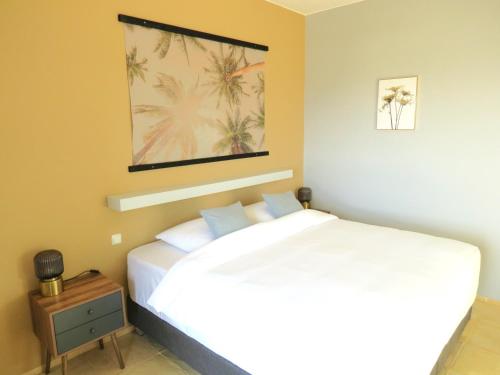 Un dormitorio con una cama blanca y una foto en la pared en MERÁKI VILLA & APARTMENTS en Vamos