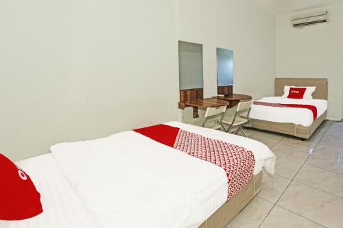 um quarto de hotel com duas camas e uma secretária em SUPER OYO 92003 Sky Airlines Guesthouse em Tangerang